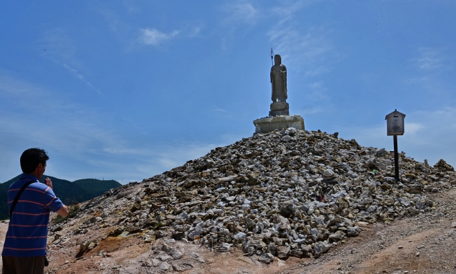 일본 아오모리의 오소레잔 보다이지의 가장 높은 곳에 선 지장보살을 향해 관람객이 기도를 올리고 있다. 지장보살 아래 쌓인 돌 하나하나는 죽은 이들을, 바람개비는 어린아이의 혼을 상징한다.