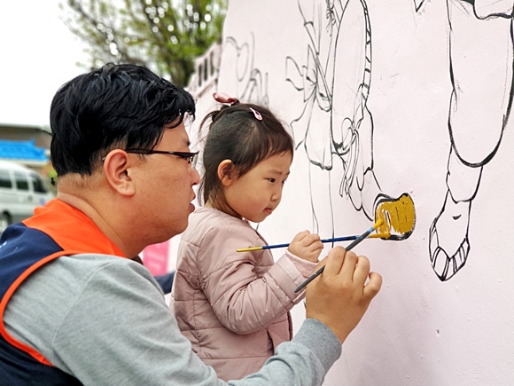 ‘우리 딸의 첫 자원봉사’라는 주제로 봉사하기록에 참여한 김원중씨와 자녀가 벽화 봉사활동을 하고 있다. 한국중앙자원봉사센터 제공