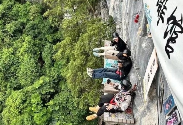 중국의 절벽 카페 이용객이 안전벨트·헬멧를 착용한 상태로 밧줄에 연결된 채 커피를 마시고 있는 모습. SNS 캡처