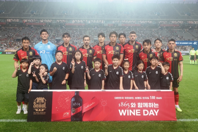 지난 22일 서울월드컵경기장에서 열린 ‘1865 와인데이’ 행사에서 1865 에스코트 키즈들과 FC서울 선수들이 함께 기념촬영을 하고 있다.  금양인터내셔날 제공