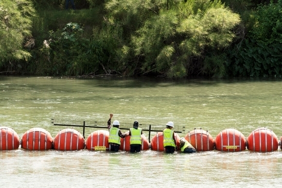 미국 텍사스주 이글패스 근처 리오그란데강에서 24일(현지시간) 밀입국자들을 차단하기 위한 수중 장벽 설치를 위해 부표들을 연결하고 있다. 이글패스 로이터 연합뉴스