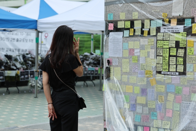 지난 25일 서울 서이초를 찾은 한 시민이 추모글을 읽으며 눈물을 닦고 있는 모습. 연합뉴스