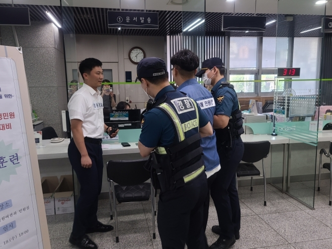 서울 성북구가 지난 19일 성북구청 통합민원실에서 진행한 악성 민원 대비 모의훈련에서 돌발 행동을 한 민원인이 경찰에 의해 밖으로 끌려 나가고 있다. 성북구 제공