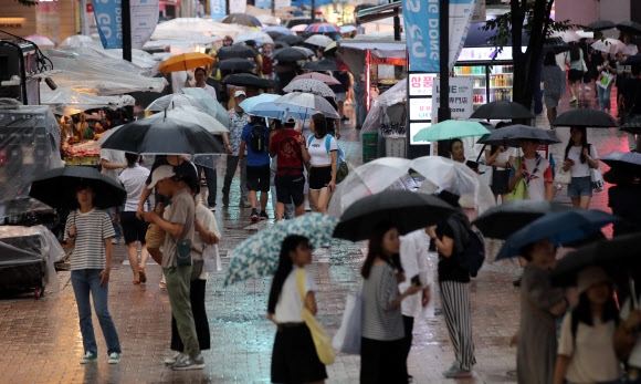 서울 서남권과 동북·서북권에 호우경보가 내려진 30일 오후 명동거리에서 우산을 쓴 시민들이 길을 걷고 있다. 2023.7.30 뉴시스