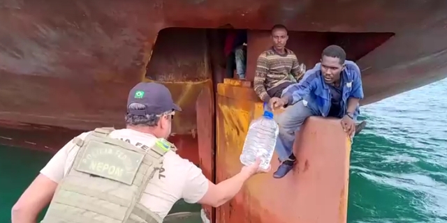 브라질 경찰관이 지난달 중순 비토리아 항구에 들어온 라이베리아 국적선 켄 웨이브 호의 꽁무니 방향타 위에 걸터앉은 나이지리아 남성들에게 생수를 건네고 있다. 브라질 연방경찰 제공 로이터