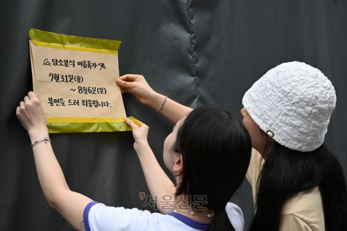지난달 31일 오후 서울 중구 남대문시장에 한 매장 주인이 여름 휴가를 알리는 안내문이 붙이고 있다. 도준석 기자
