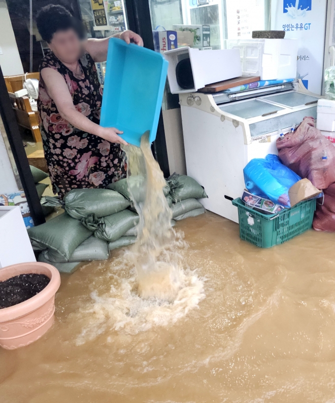 강원 고성군 거진읍 거진리의 한 가게에서 상인이 가게에 들어찬 물을 퍼내고 있다.  고성 연합뉴스