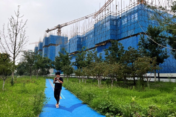 지난 11일 한 주민이 중국 베이징의 비구이위안(컨트리가든) 아파트 단지 건설 현장을 지나가고 있다. 베이징 로이터 연합뉴스