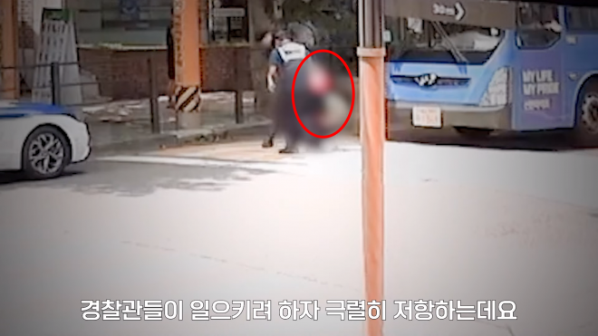 지난달 31일 서울 용산구 도로에서 신호 대기 중이던 버스 앞에서 한 여성이 “문을 열어달라”며 난동을 부렸다. 이 여성은 신호가 파란불로 바뀌었음에도 버스 앞을 가로막고 항의했다. 경찰이 여성을 일으키는 장면. 서울경찰 유튜브
