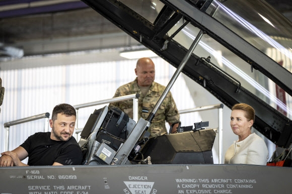 볼로디미르 젤렌스키(왼쪽) 우크라이나 대통령이 20일(현지시간) 덴마크의 보이엔스에 있는 스크리드스트룹 공군기지에서 F16 전투기에 앉아 메트 프레데릭센 덴마크 총리와 얘기를 나누고 있다. 보이엔스 AP 연합뉴스