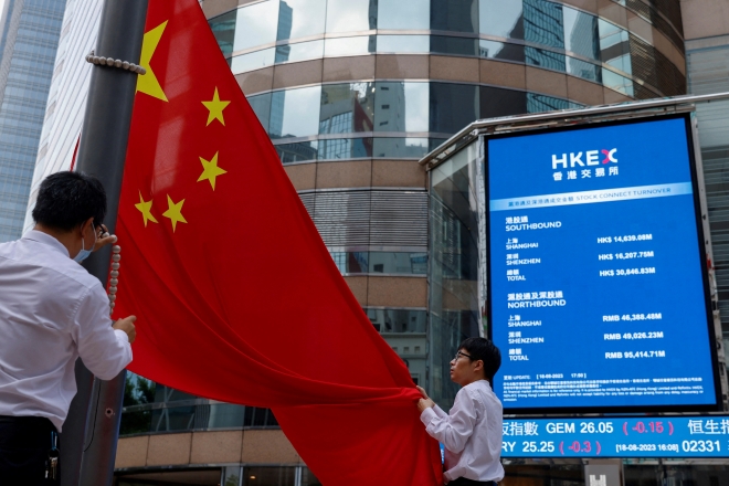 18일(현지시간) 홍콩증권거래소 밖 항셍지수 전광판 앞에서 직원들이 중국 국기를 거두고 있다. 2023.8.28 로이터 연합뉴스