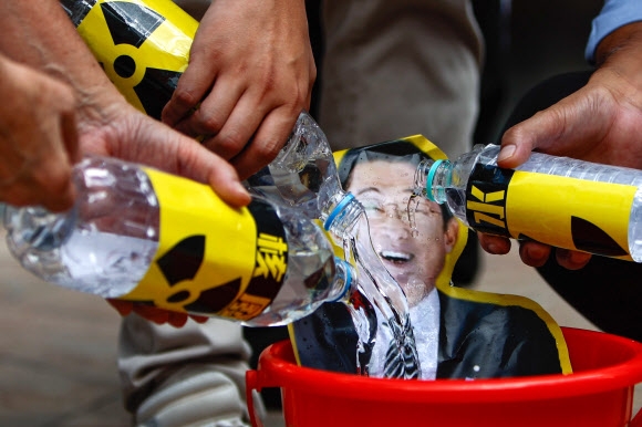 홍콩 어민들이 지난 23일 주홍콩 일본총영사관 앞에서 기시다 후미오 일본 총리의 얼굴 사진에 ‘방사능수’라고 적힌 물병을 이용해 물을 부으며 후쿠시마 오염수 해양 방류 반대 시위를 벌이고 있다.  홍콩 EPA 연합뉴스
