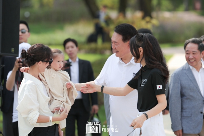 윤석열 대통령과 부인 김건희 여사가 26일 서울 용산어린이정원 내 분수정원에서 열린 다둥이가족 초청 행사에 깜짝 방문해 어린이와 인사하고 있다. 윤 대통령 부부가 나란히 입고 있는 ‘천안함 티셔츠’가 눈에 띈다. 2023.8.26 대통령실 제공