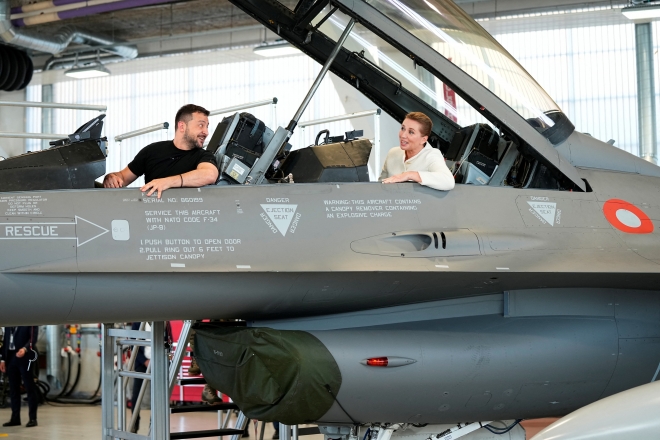 20일(현지시간) 깜짝 순방에 나선 볼로디미르 젤렌스키 우크라이나 대통령이 덴마크 보옌스에 있는 스크리드스트럽 공군기지 격납고에서 메테 프레데릭센(뒤) 덴마크 총리와 F-16 전투기에 앉아 있다. 2023.8.20 로이터 연합뉴스