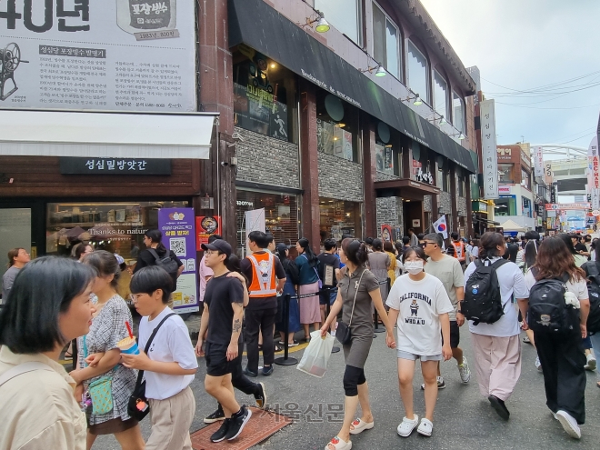 지난 15일 0시 축제 방문객들이 성심당 본점 앞을 지나가고 있다. 그 옆으로 빵을 사려는 사람들이 건물 벽을 따라 길게 줄 서 있다. 대전 이천열 기자