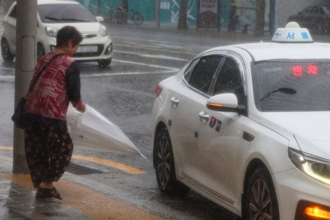 많은 비가 내린 23일 오후 서울 노원구 공릉역 인근에서 한 시민이 택시를 잡아타고 있다. 2023.8.23 연합뉴스
