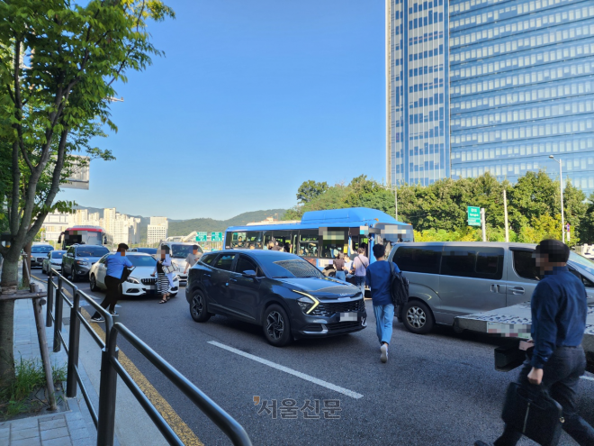 7일 오전 서울 서초구 양재대로 한가운데 정차한 버스를 타고 내리기 위해 승객들이 도로를 건너고 있다.