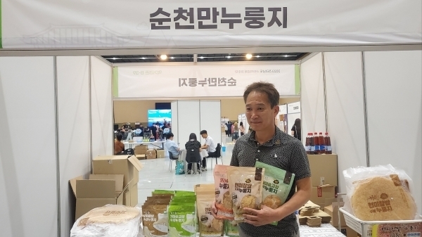 2023 전라남도 사회적 경제 한마당 행사에 참여한 김종훈 순천만누룽지 대표가 누룽지 상품을 들고 홍보하고 있다.