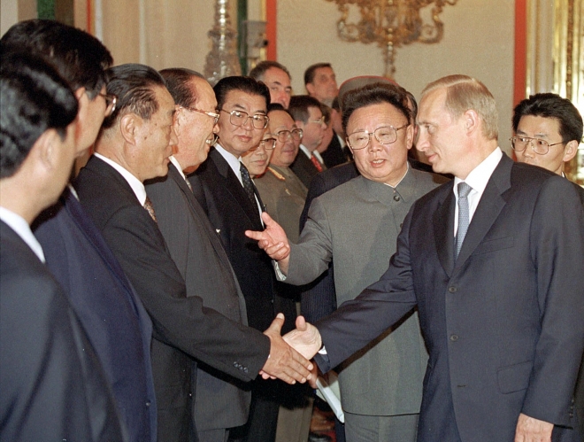 2001년 8월 4일 모스크바 크렘린궁에서 블라디미르 푸틴 러시아 대통령(오른쪽)이 대표단과 확대 회담에 앞서 악수하는 동안 북한 지도자 김정일(가운데)이 손짓하고 있다. 서울신문DB
