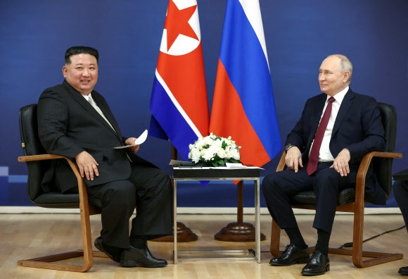김정은 북한 국무위원장(왼쪽)과 블라디미르 푸틴 러시아 대통령이 13일(현지시간) 러시아 아무르주 보스토치니 우주기지에서 마주 앉아 웃음짓고 있다. 보스토치니 로이터 연합뉴스