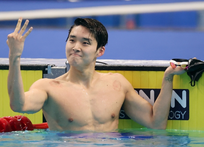 수영 남자 자유형 400m 결승에서 김우민이 금메달을 따고는 손가락 3개를 펴들고 3관왕을 자축하고 있다.