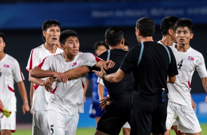 북한 남자축구 대표팀이 항저우 아시안게임 8강전에서 일본에 패한 뒤 주심에게 거칠게 항의하고 있다. AP연합뉴스