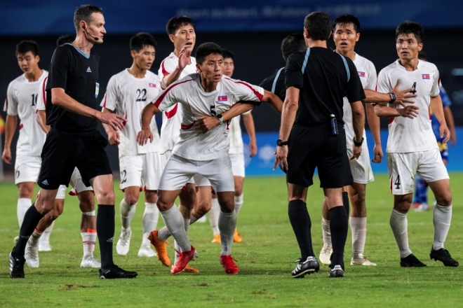 북한 남자축구 대표팀이 항저우 아시안게임 8강전에서 일본에 패한 뒤 주심에게 거칠게 항의하고 있다. AP연합뉴스