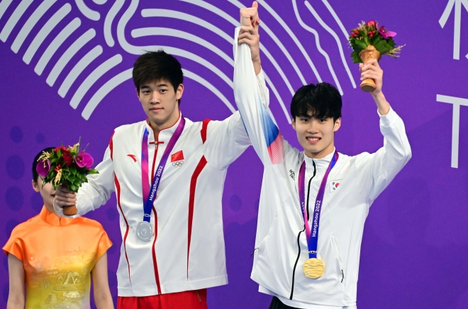 지난달 27일 중국 항저우 올림픽 스포츠센터 수영장에서 열린 2022 항저우 아시안게임 수영 남자 자유형 200ｍ에서 금메달을 차지한 황선우(오른쪽)가 은메달을 획득한 중국의 판잔러와 함께 손을 들고 있다. 항저우 오장환 기자