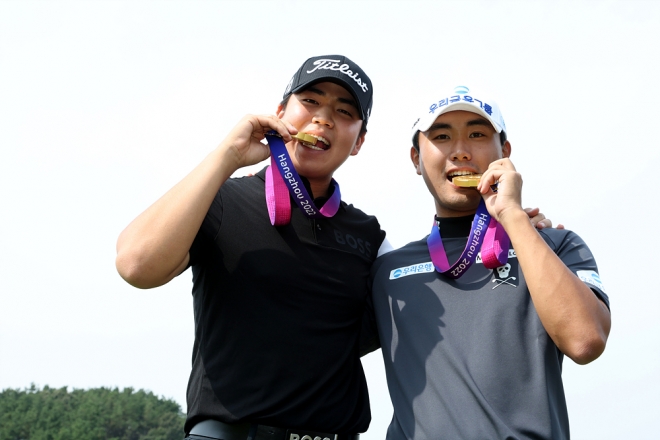 4일 최경주 인비테이셔널 기자회견을 앞두고 장유빈(왼쪽)과 조우영이 2022 항저우 아시안게임 남자 골프 단체전에서 따낸 금메달을 깨물며 기념사진을 찍고 있다. KPGA 제공