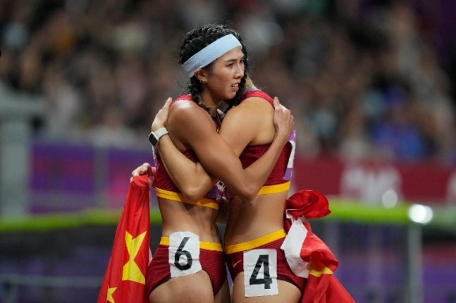 지난 1일 항저우 아시안게임 여자 육상 100ｍ 허들 결승전에서 금메달을 딴 중국 린위웨이가 동료 우옌니를 포옹하는 모습. 연합뉴스