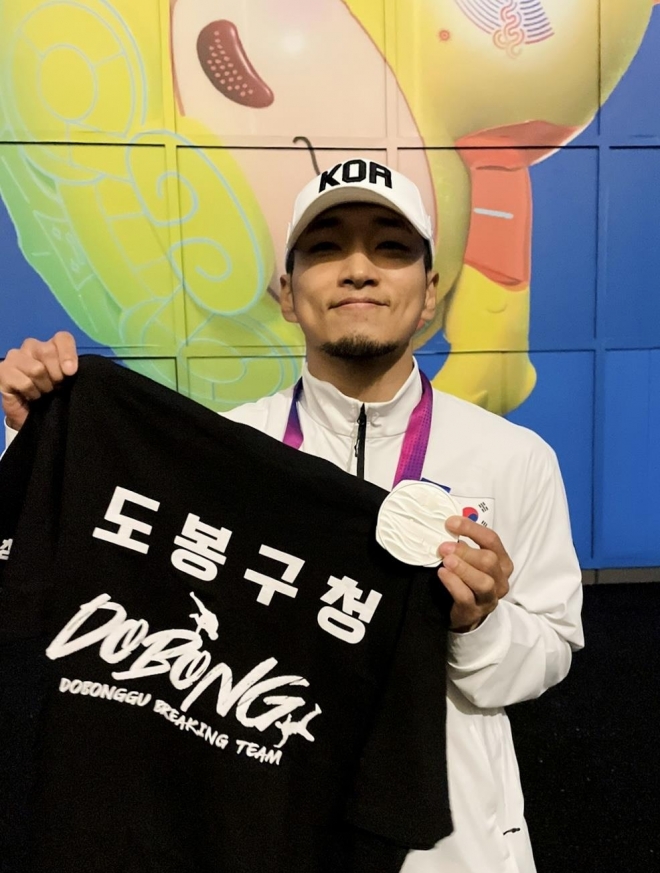 도봉구청 브레이킹 소속 김홍열(Hong10) 선수가 2022 항저우 아시안게임 브레이킹 종목에서 은메달을 획득한 뒤 팀 티셔츠를 들고 기념촬영을 하고 있다. 도봉구 제공