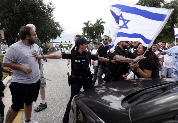 미국 플로리다주 포트 로더데일에서 8일(현지시간) 이스라엘을 지지하는 시위대와 팔레스타인을 지지하는 시위대가 충돌하려 하자 경찰관이 뜯어 말리고 있다. 사우스 플로리다 선센티널 AP 연합뉴스