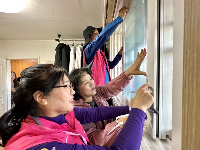 고효율 창호 간편시공 사업의 시연 행사에서 봉양순 위원장(가운데)이 시공 세대를 방문해 덧유리와 방풍재 등을 손수 설치하고 있다.