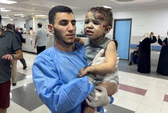 팔레스타인 가자시티에 있는 시프트 병원 응급의가 15일(현지시간) 이스라엘 공습에 다친 소년을 치료한 뒤 옮기고 있다. 가자시티 로이터 연합뉴스
