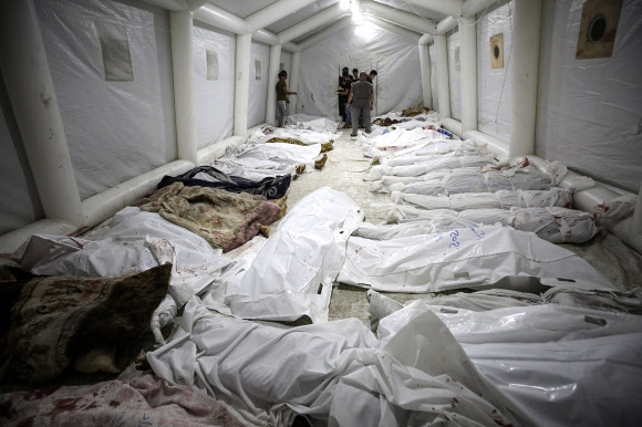17일(현지시간) 팔레스타인 가자시티의 알아흘리 병원에서 이스라엘군의 공습에 희생된 이들의 주검이 근처 알시파 병원 앞마당 임시 텐트에 옮겨져 있다. 가자시티 AP 연합뉴스