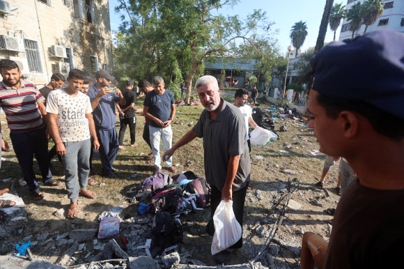 전날 폭발로 무참한 인명이 희생된 가자시티 알아흘리 아랍병원마당에서 18일 사람들이 모여 얘기를 나누고 있다. 바닥에 희생자와 부상자들이 남긴 옷가지와 이불 같은 것들이 눈에 들어온다. 가자시티 로이터 연합뉴스