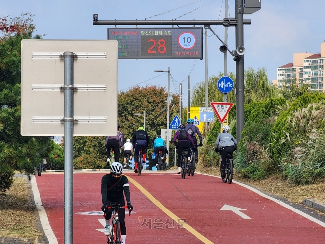 22일 서울 강동구 한강공원 광나루지구 자전거도로에서 라이더들이 무리 지어 빠른 속도로 지나가고 있다. 안내판에 보행자 건널목이 앞에 있으니 속도를 10㎞ 이하로 낮추라고 권고돼 있지만 속도계에는 이를 초과하는 시속 28㎞가 찍혀 있다.