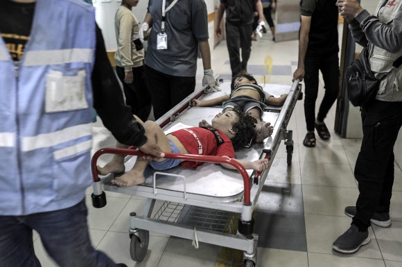 이스라엘군의 공습에 다친 어린이들이 26일(현지시간) 팔레스타인 가자지구 칸 유니스의 한 병원에 실려오고 있다. 가자지구 보건부는 이스라엘의 보복 공습에 숨진 이들이 7000명을 넘어섰다고 발표했다. 칸 유니스 EPA 연합뉴스
