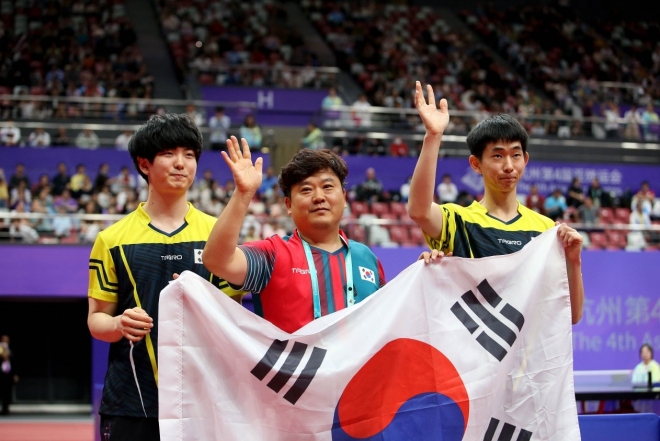 한국 탁구 국가대표 김창기(오른쪽)-김기태가 28일 중국 항저우 궁수 캐널 스포츠파크 체육관에서 열린 2022 항저우아시안패러게임 MD22 남자 복식 결승전에서 승리한 뒤 김정중 코치와 태극기를 들고 기뻐하고 있다. 대한장애인체육회 제공