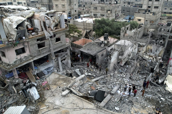 팔레스타인 주민들이 밤새 누세이랏 난민 캠프에 이스라엘군의 공습이 쏟아져 처참한 몰골을 드러낸 건물들 주변을 29일(현지시간) 살펴보고 있다. 누세이랏 AP 연합뉴스