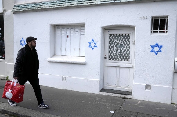 한 남성이 31일(현지시간) 프랑스 파리 14구의 한 주택 건물 벽에 그려진 ‘다윗의 별’들을 바라보며 지나가고 있다. 파리 AP 연합뉴스