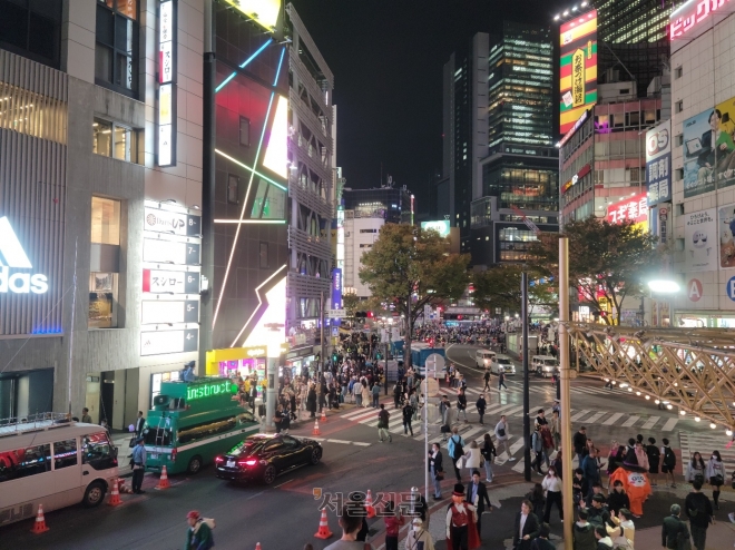 핼러윈 당일인 31일 일본 최대 번화가인 도쿄 시부야역 인근 거리에서 개조된 차량 위에 올라선 경찰(왼쪽)이 군중 분산을 유도하고 있다.