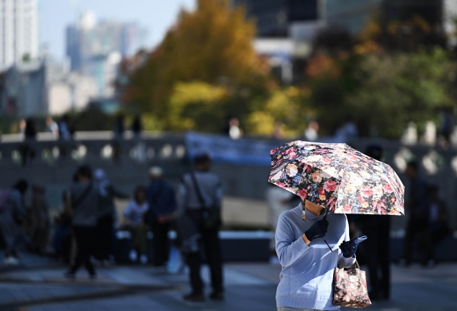 낮 최고기온이 25~29도로 더운 날씨를 보인 2일 서울 종로구 청계천에서 한 시민이 양산을 쓰고 이동하고 있다. 홍윤기 기자