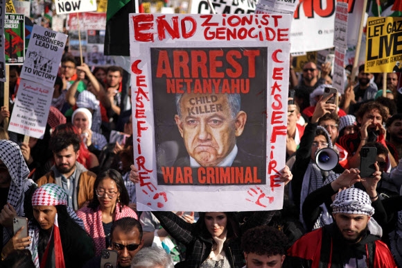 지난 4일(현지시간) 미국 워싱턴DC의 자유의 광장에서 팔레스타인 지지 집회가 열린 가운데 한 참가자가 베냐민 네타냐후 이스라엘 총리를 즉각 체포해야 한다는 포스터를 들어 보이고 있다. AFP 자료사진 연합뉴스