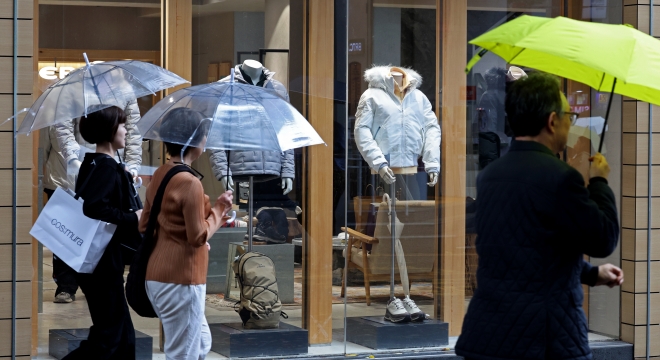 절기상 입동을 이틀 앞두고 올가을 첫 한파특보가 발효된 6일 서울 중구 명동거리에서 우산을 쓴 시민이 겨울옷이 진열된 옷 가게 앞을 지나고 있다. 2023.11.6 뉴시스