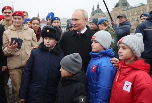 블라디미르 푸틴 러시아 대통령이 4일 모스크바 붉은 광장에서 열린 국민통합의 날 헌화 행사에 우크라이나 전쟁중 사망한 이들의 유족과 함께 참석해 사진을 찍고 있다. 모스크바 epa 연합뉴스