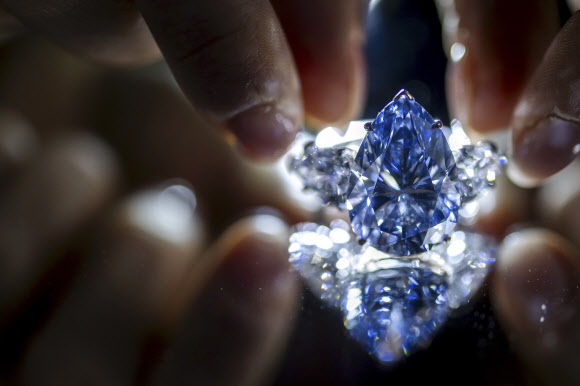 크리스티 경매의 한 직원이 지난 2일(현지시간) 스위스 제네바에서 배 모양의 희귀 블루다이아몬드를 경매에 앞서 소개하고 있다. 이 보석은 7일 4380만 달러에 팔렸다. AP 자료사진 연합뉴스