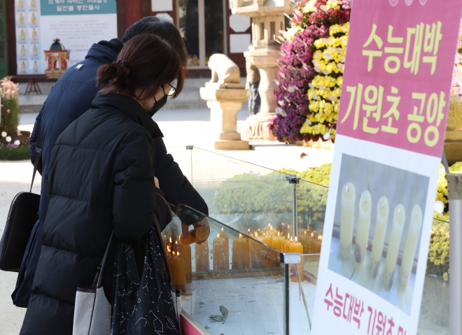 오는 16일 치러지는 2024학년도 대입수학능력시험을 나흘 앞둔 12일 오후 서울 종로구 조계사 대웅전 앞에서 한 학부모가 합격 기원 촛불에 불을 붙이고 있다. 연합뉴스