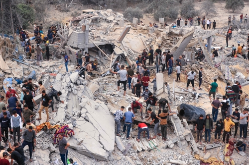 12일(현지시간) 이스라엘군의 공습을 받은 가자지구 칸 유니스 주민들이 파괴된 건물 잔해 속에서 생존자를 찾고 있다. 하마스가 통치하는 가자지구 보건부에 따르면 지난 7일 하마스와 이스라엘 간 전쟁이 시작된 이후 가자지구 측 사망자는 1만 명에 달한다. 칸유니스 AFP=연합뉴스