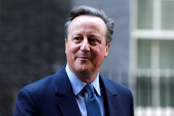 데이비드 캐머런 전 영국 총리가 13일(현지시간) 새 외무 장관으로 임명된 뒤 다우닝가 10번지 총리 관저 바깥으로 걸어나오며 웃고 있다. 런던 로이터 연합뉴스
